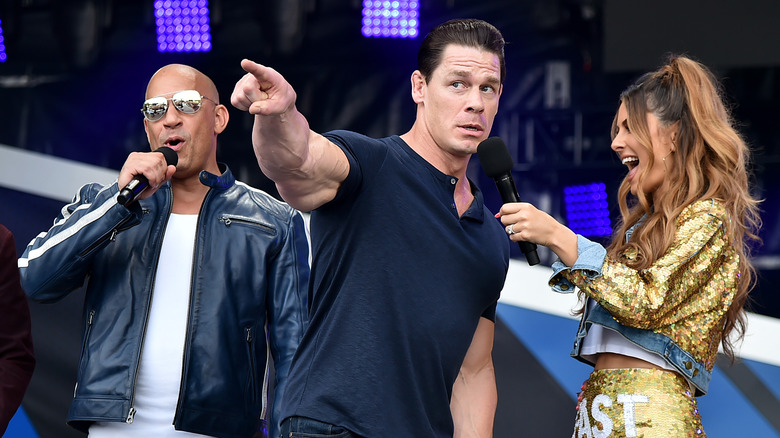 Vin Diesel, John Cena, and Maria Menounos speaking into microphones