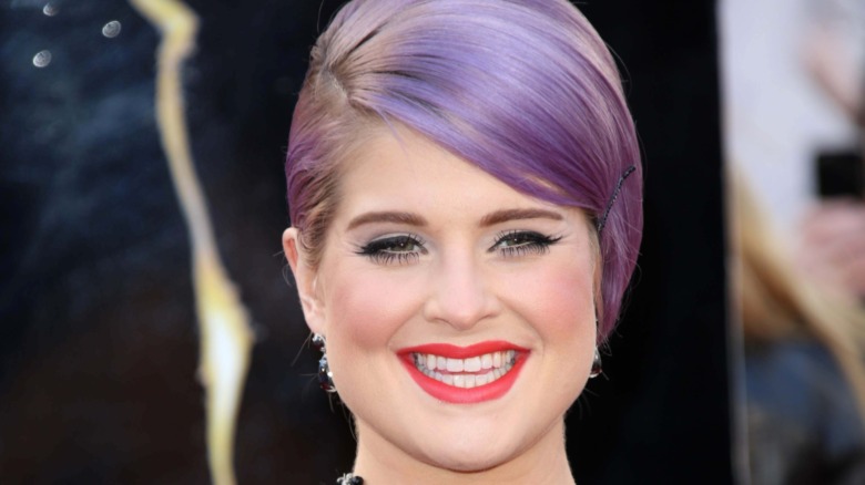 Kelly Osbourne smiling purple hair red lipstick