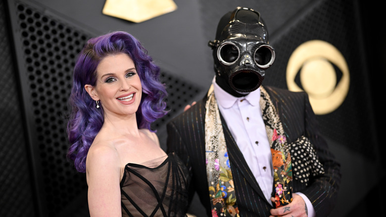 Kelly Osbourne smiling; Sid Wilson wearing gas mask