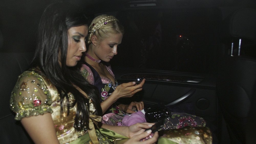 Kim Kardashian and Paris Hilton both seated in a car, texting