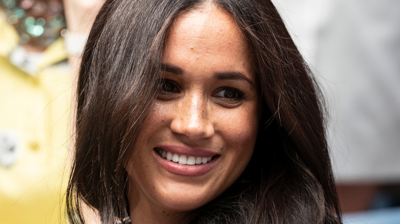 Meghan Markle smiling and looking to the side