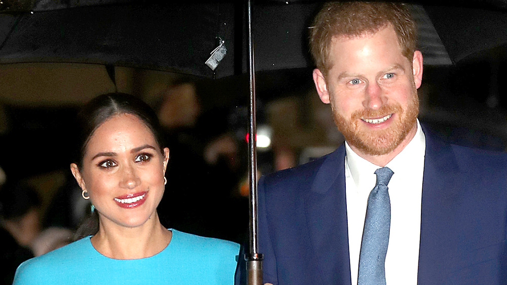 Meghan Markle and Prince Harry walking in the rain under an umbrella