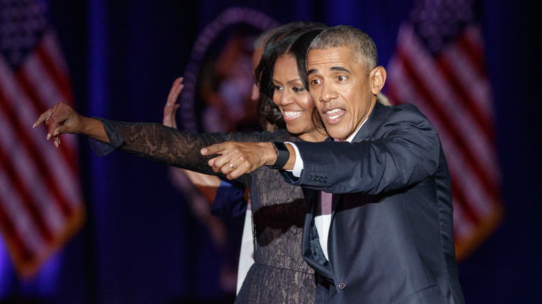 Barack and Michelle Obama pointing to crowd at an event 