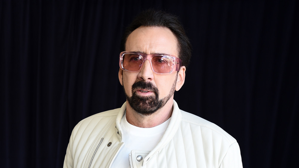 portrait of Nicolas Cage in a white jacket and pink sunglasses