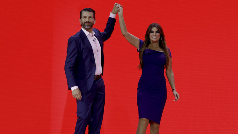 Donald Trump Jr. and Kimberly Guilfoyle holding hands on stage