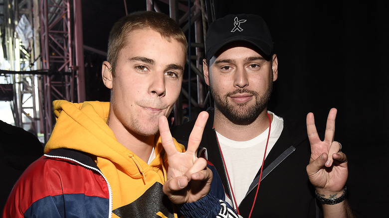 Justin Bieber and Scooter Braun giving peace signs in 2017