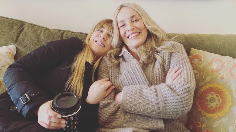 Kaley Cuoco and Sharon Stone smiling on the couch