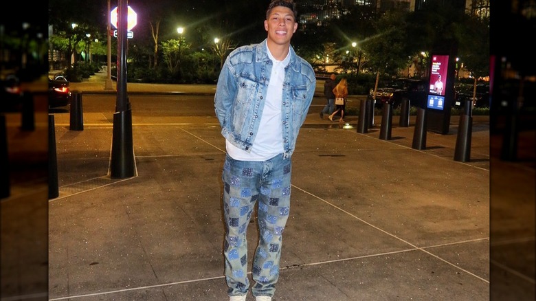 Jackson Mahomes stands on sidewalk in blue denim jacket