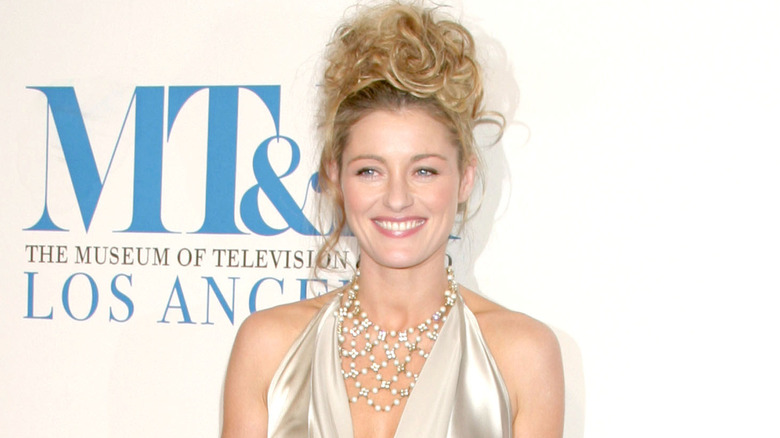 Louise Lombard smiling, wearing hair in an updo