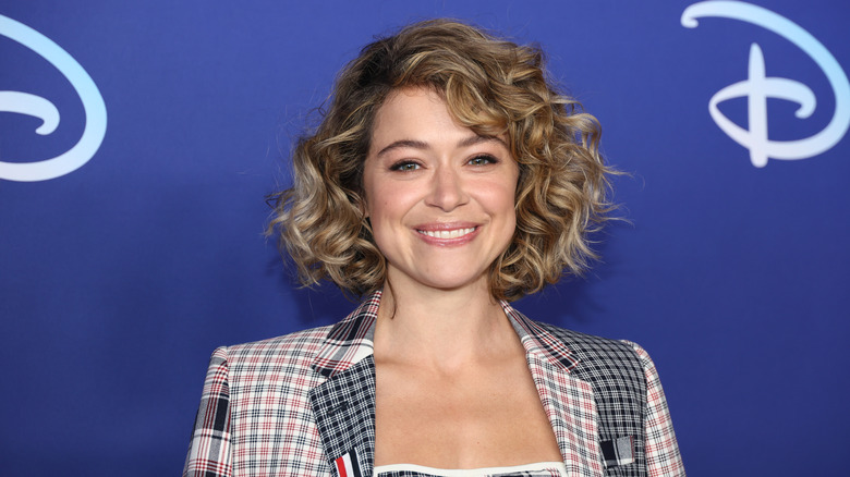 Tatiana Maslany with curly hair, wearing plaid suit