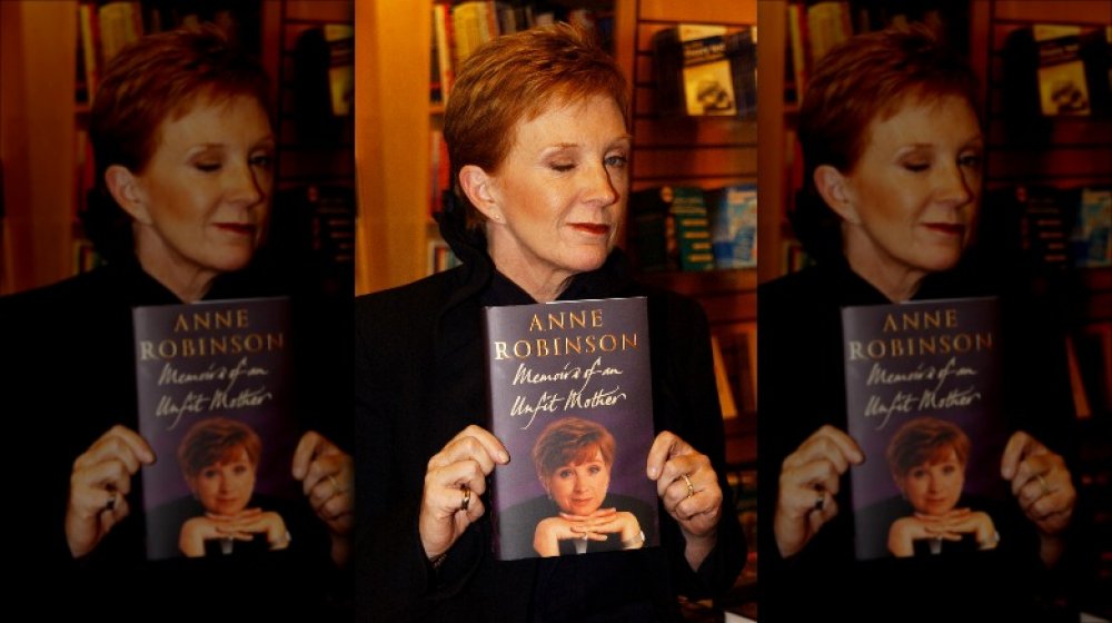 Anne Robinson winking while holding up her memoir