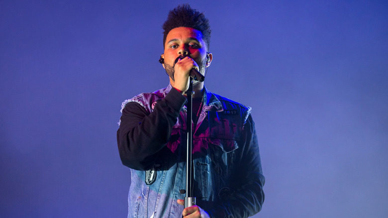 The Weeknd sings into a microphone