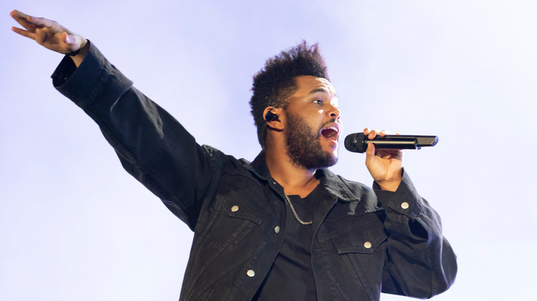 The Weeknd singing onstage with arm outstretched