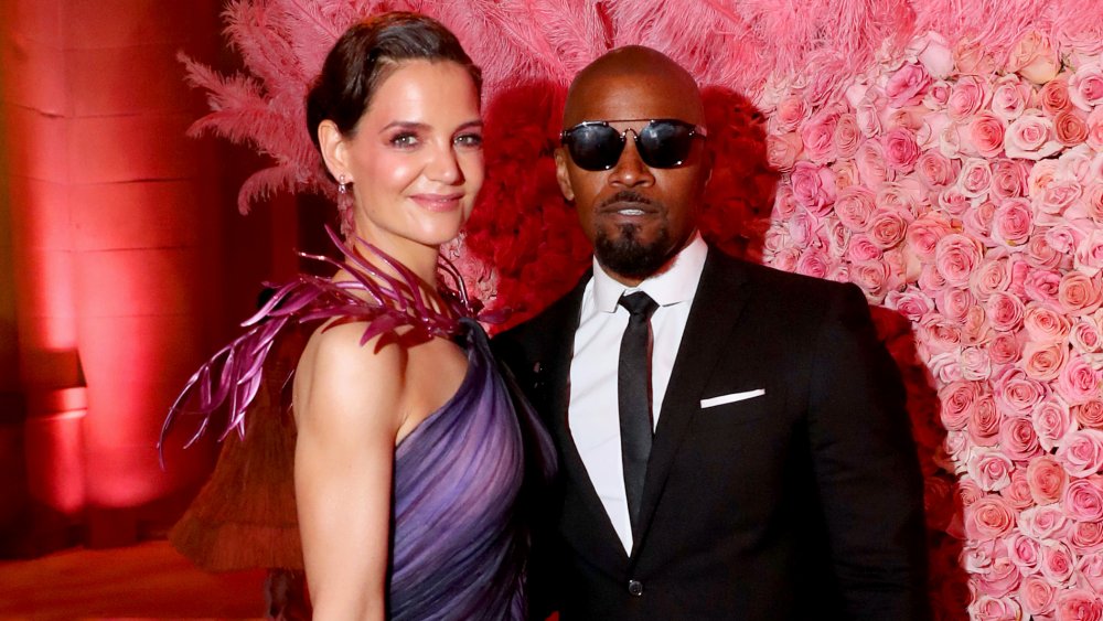 Katie Holmes and Jamie Foxx smiling on a red carpet 