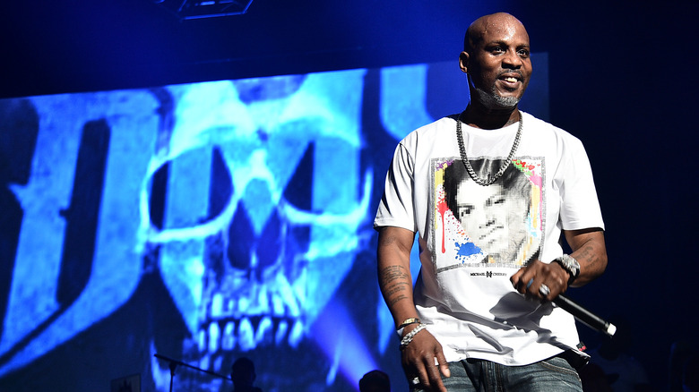 DMX, performing at a 2019 show, smiling, wearing jeans, holding a microphone