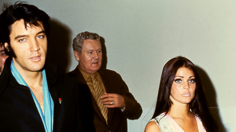 Elvis Presley walking with then-wife Priscila Presley and father Vernon Presley