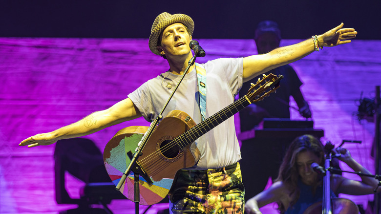 Jason Mraz posed with his arms out wide with a guitar