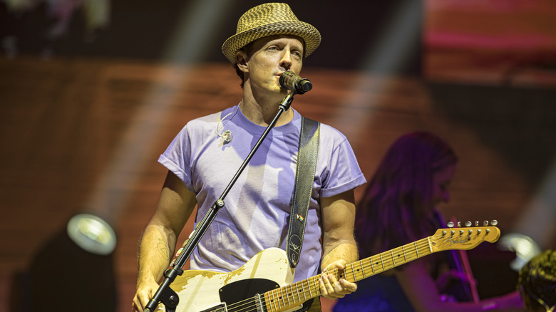 Jason Mraz holding a guitar and singing on stage