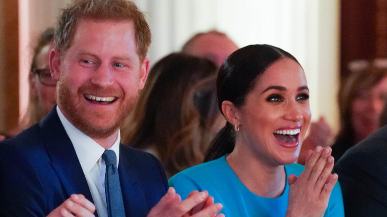 Prince Harry and Meghan Markle laughing and clapping