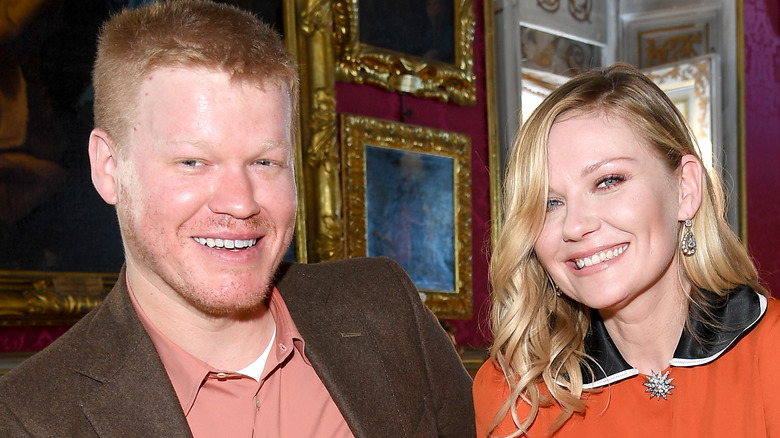 Jesse Plemons and Kirsten Dunst smiling paintings background