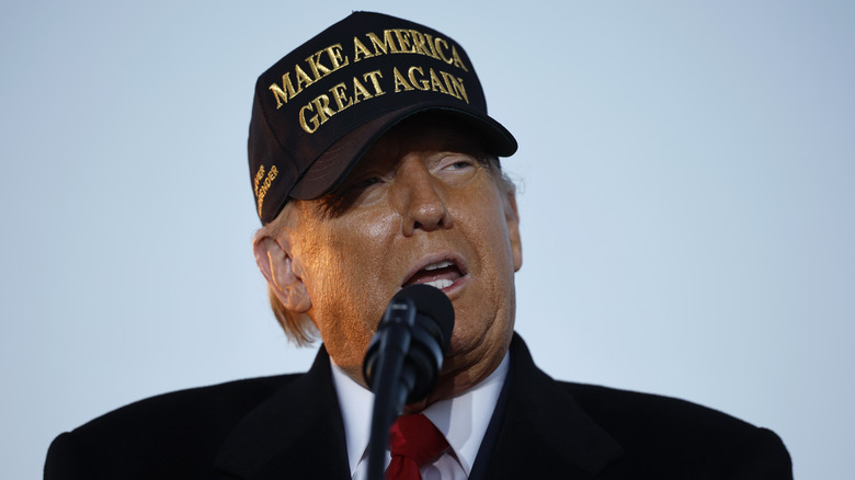 Donald Trump wearing a black and gold "Make America Great Again" hat at a campaign rally