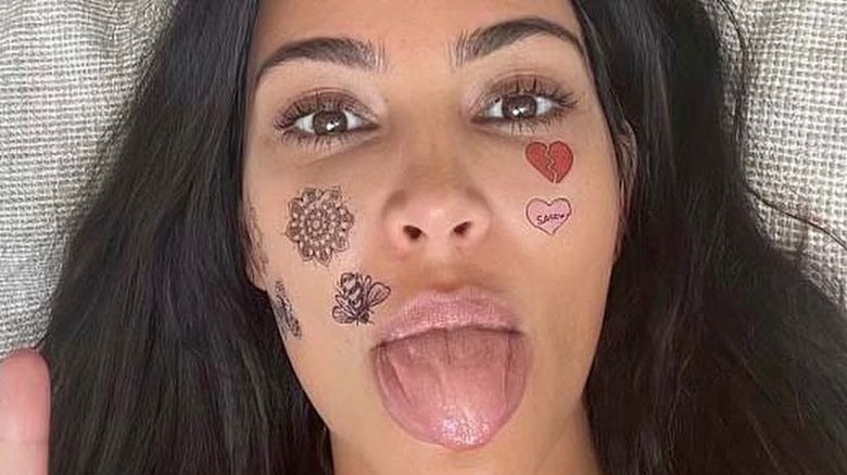 Kim Kardashian sticking tongue out with fake tattoos