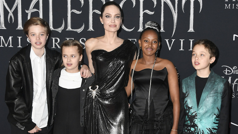 Zahara Jolie wearing a black dress and posing with her family at the Hollywood premiere of Maleficent: Mistress of Evil